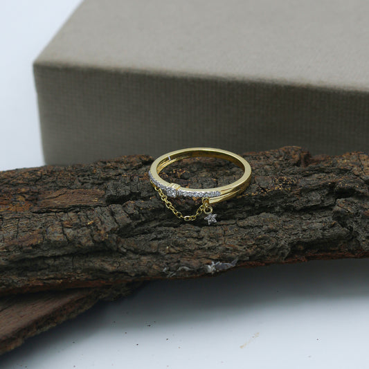 Gold ring with a chain and star detail on a wooden surface