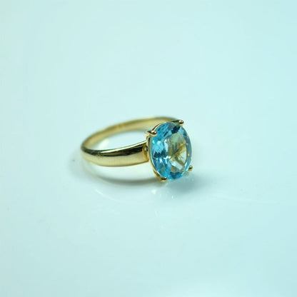 Gold ring with a blue gemstone on a light blue background