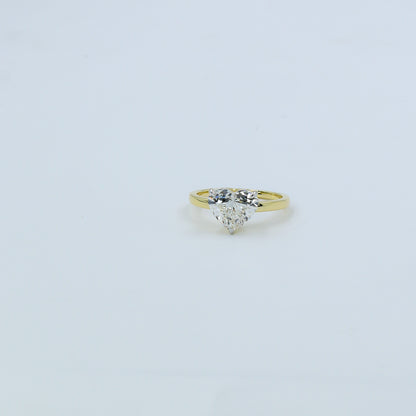 Gold ring with a heart-shaped diamond on a light gray background