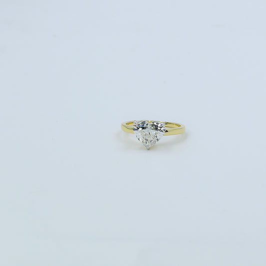 Gold ring with a heart-shaped diamond on a light gray background
