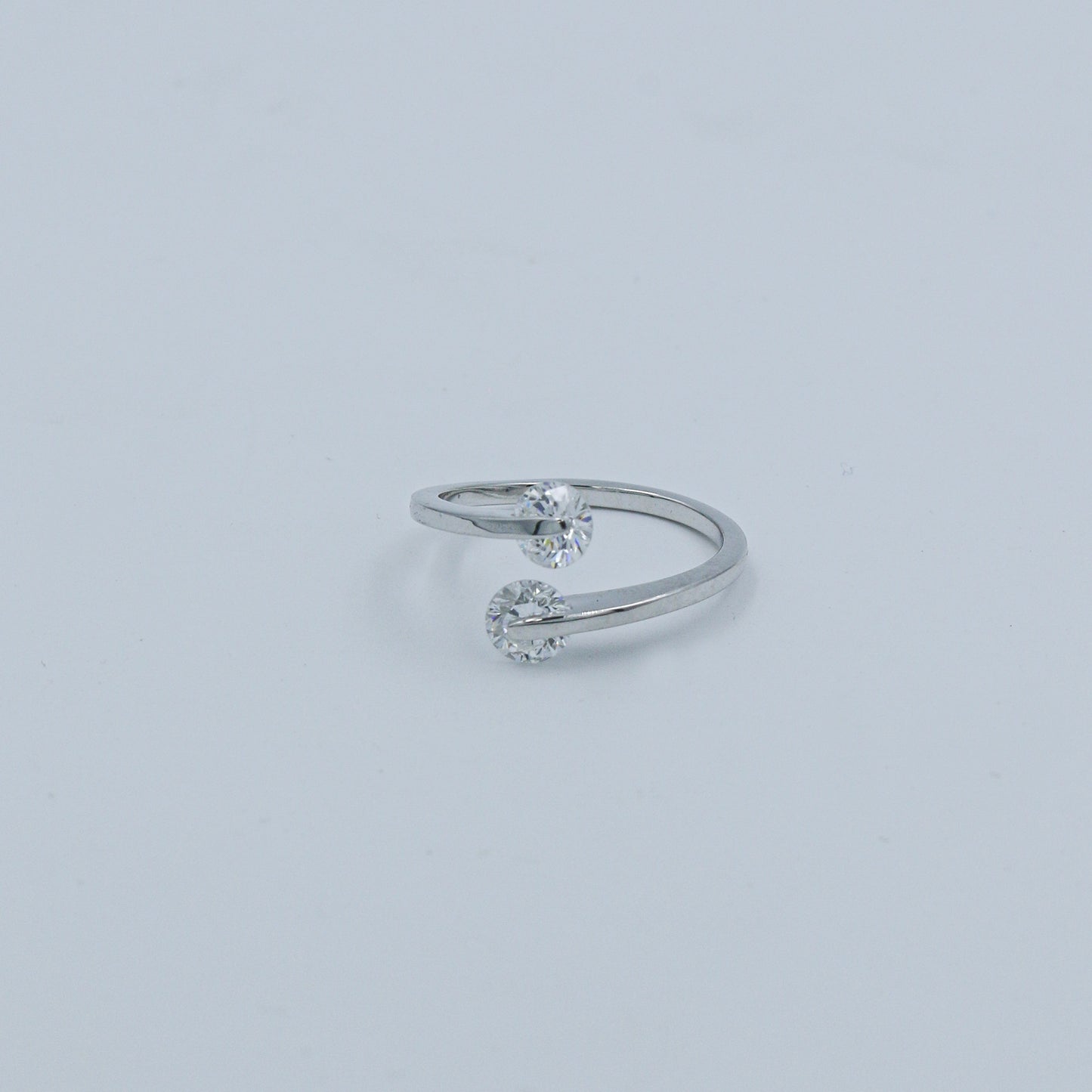 Silver ring with two small diamonds on a light gray background