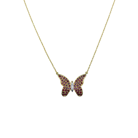 Butterfly-shaped pendant with red gemstones on a gold chain against a light gray background