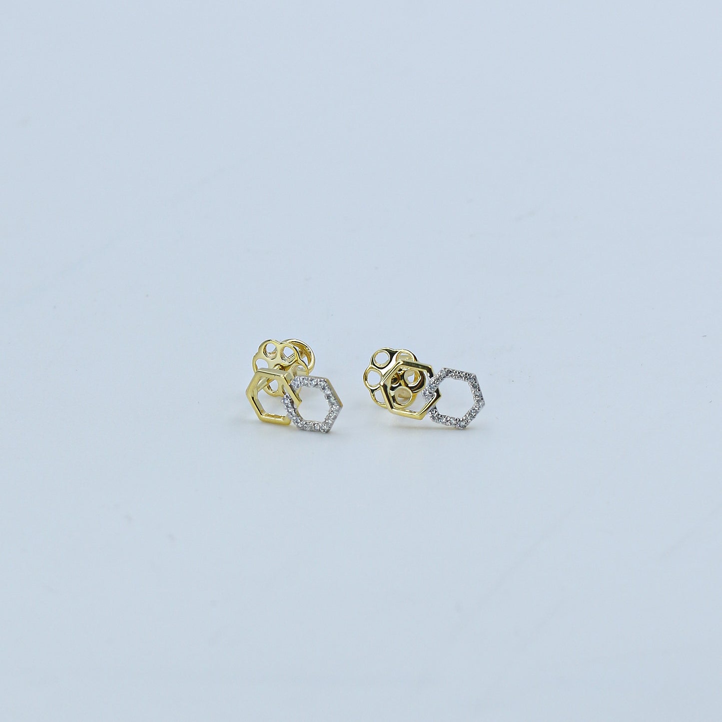 Pair of gold and silver earrings on a light gray background