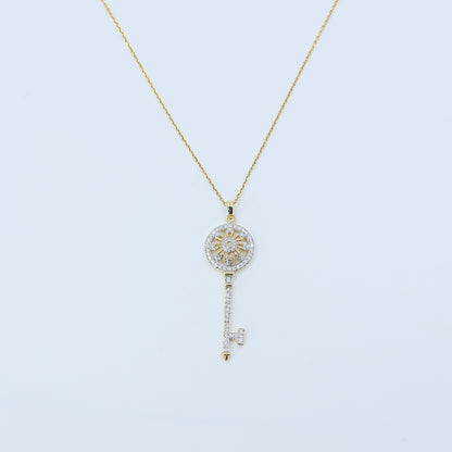 Gold necklace with a key-shaped pendant on a light blue background