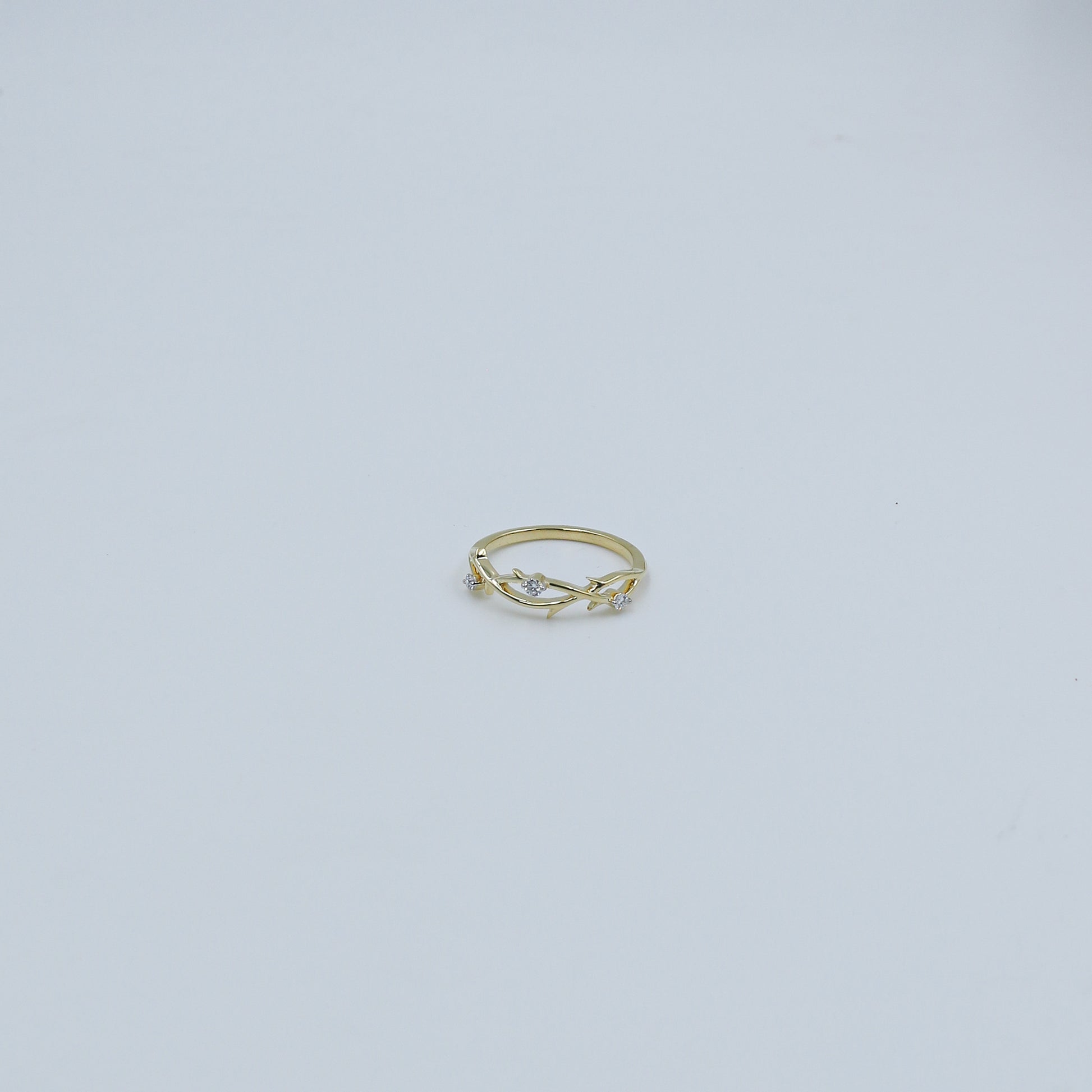 Gold ring with small diamonds on a light gray background