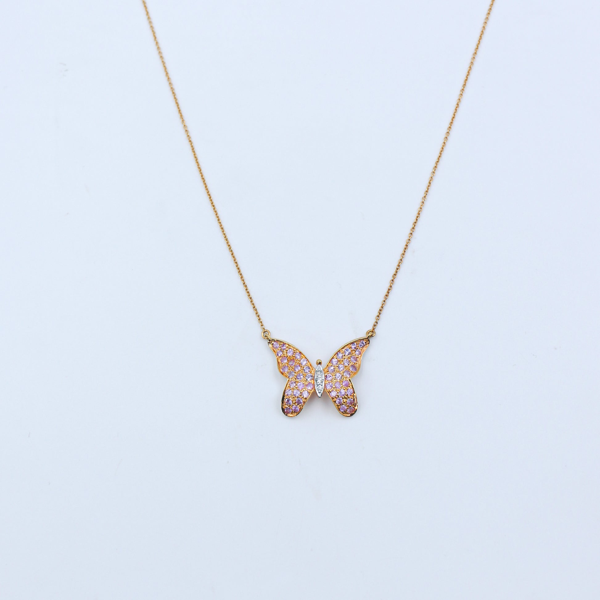 Butterfly-shaped necklace with pink gemstones on a light blue background