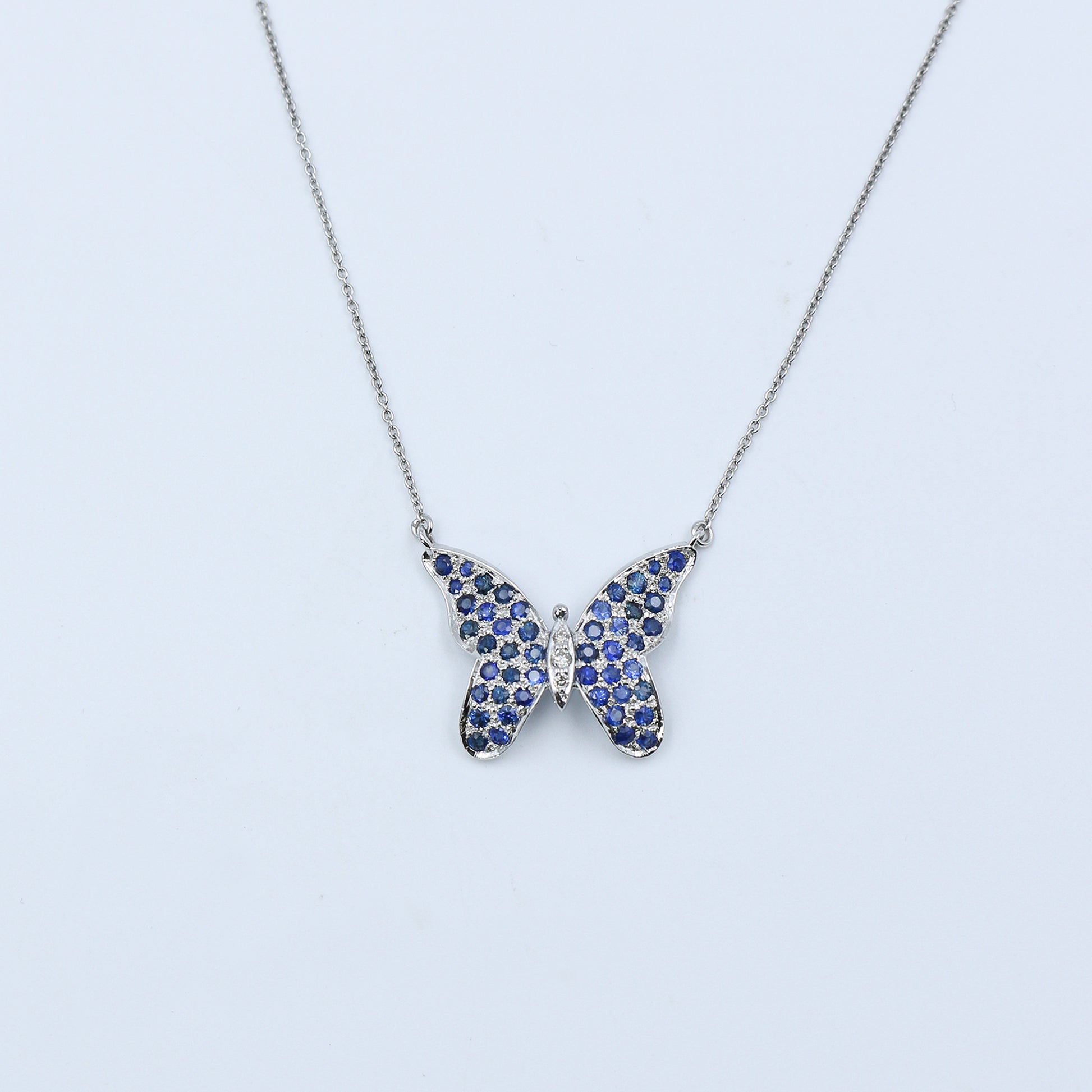 Butterfly-shaped necklace with blue gemstones on a light gray background