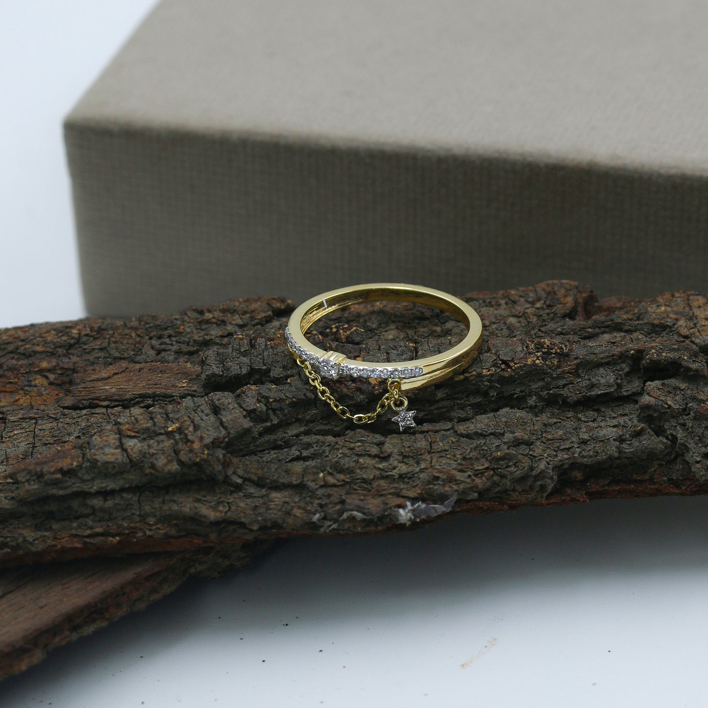 Gold ring with a chain and star detail on a wooden surface