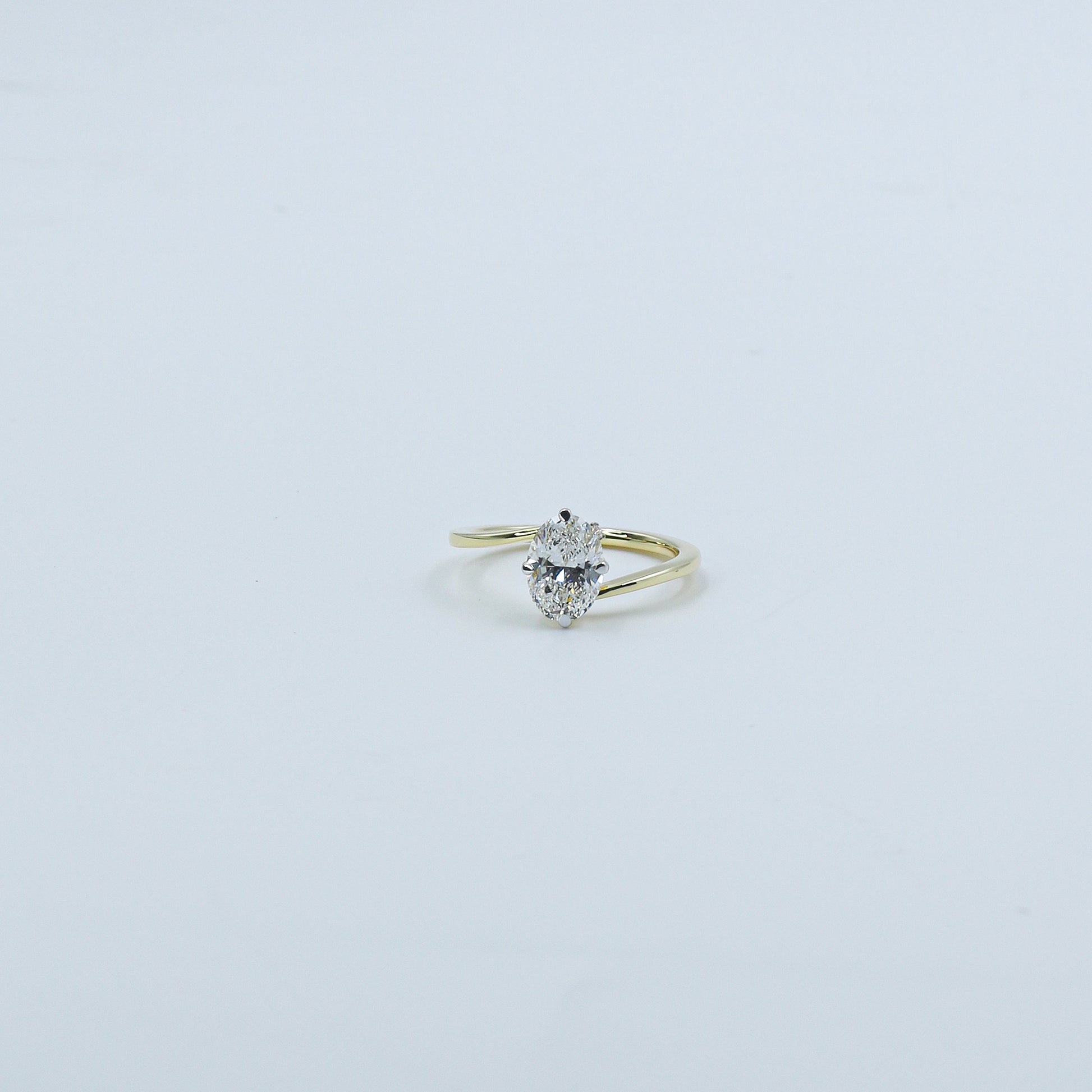 Gold ring with a heart-shaped diamond on a light gray background