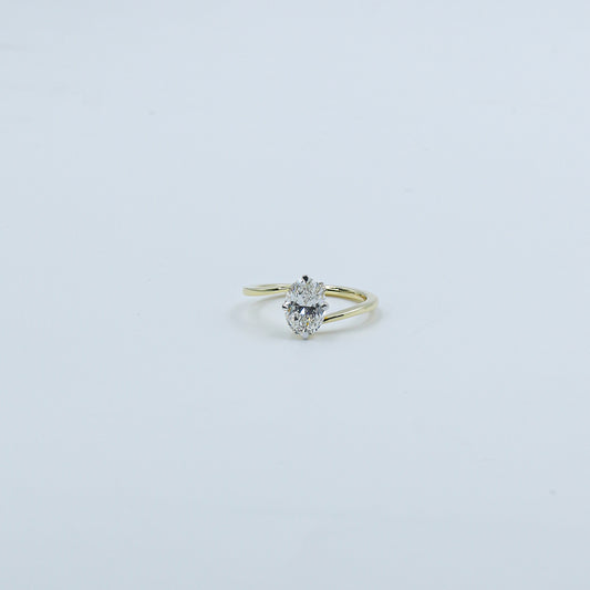Gold ring with a heart-shaped diamond on a light gray background