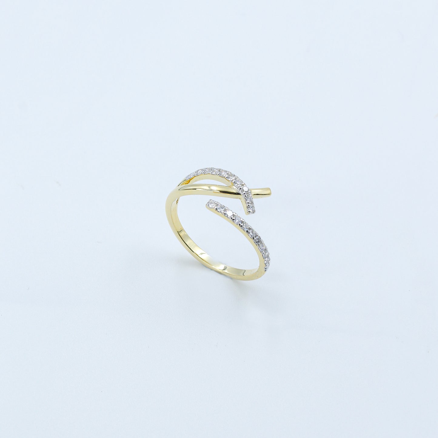 Gold open ring with embedded diamonds on a light gray background
