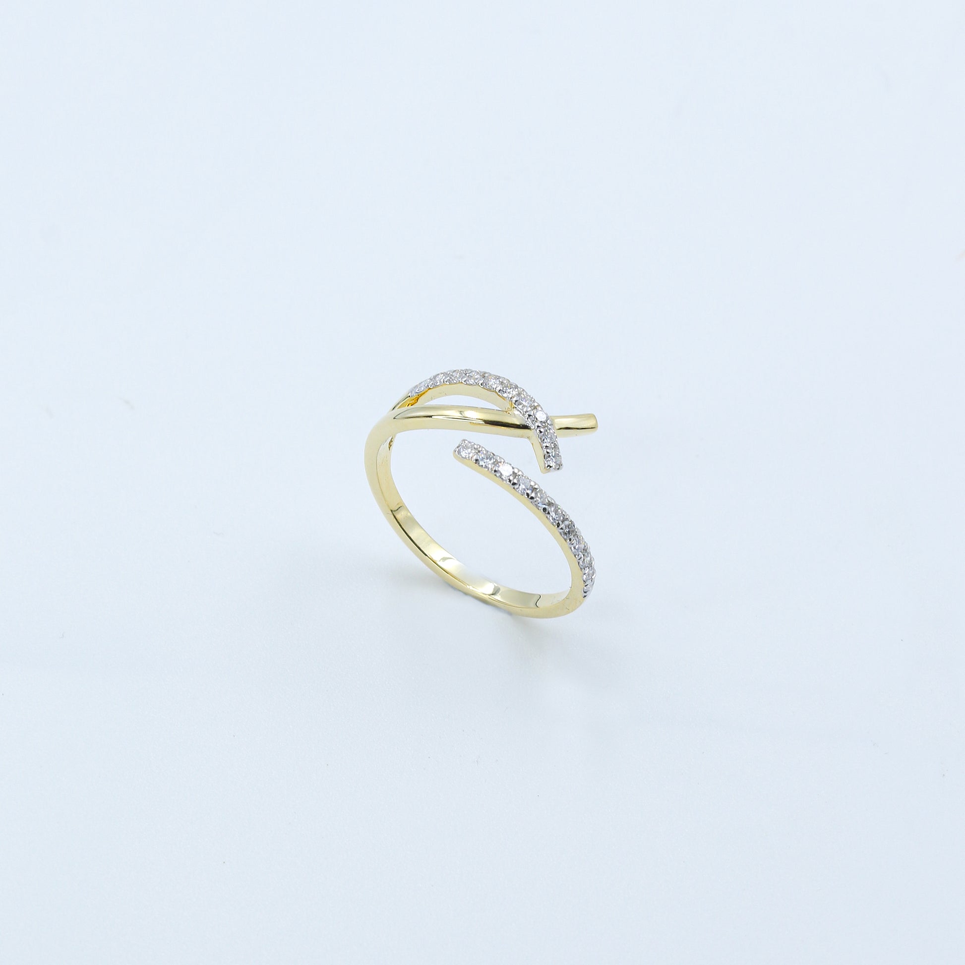 Gold open ring with embedded diamonds on a light gray background