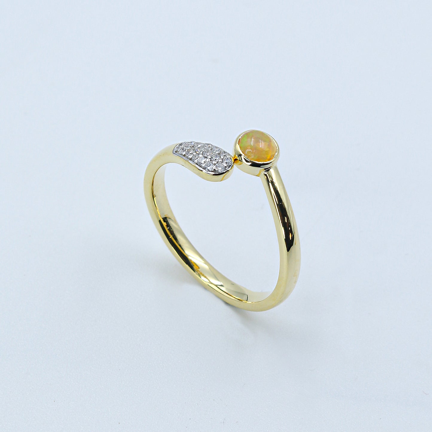 Gold ring with a green gemstone on a light gray background