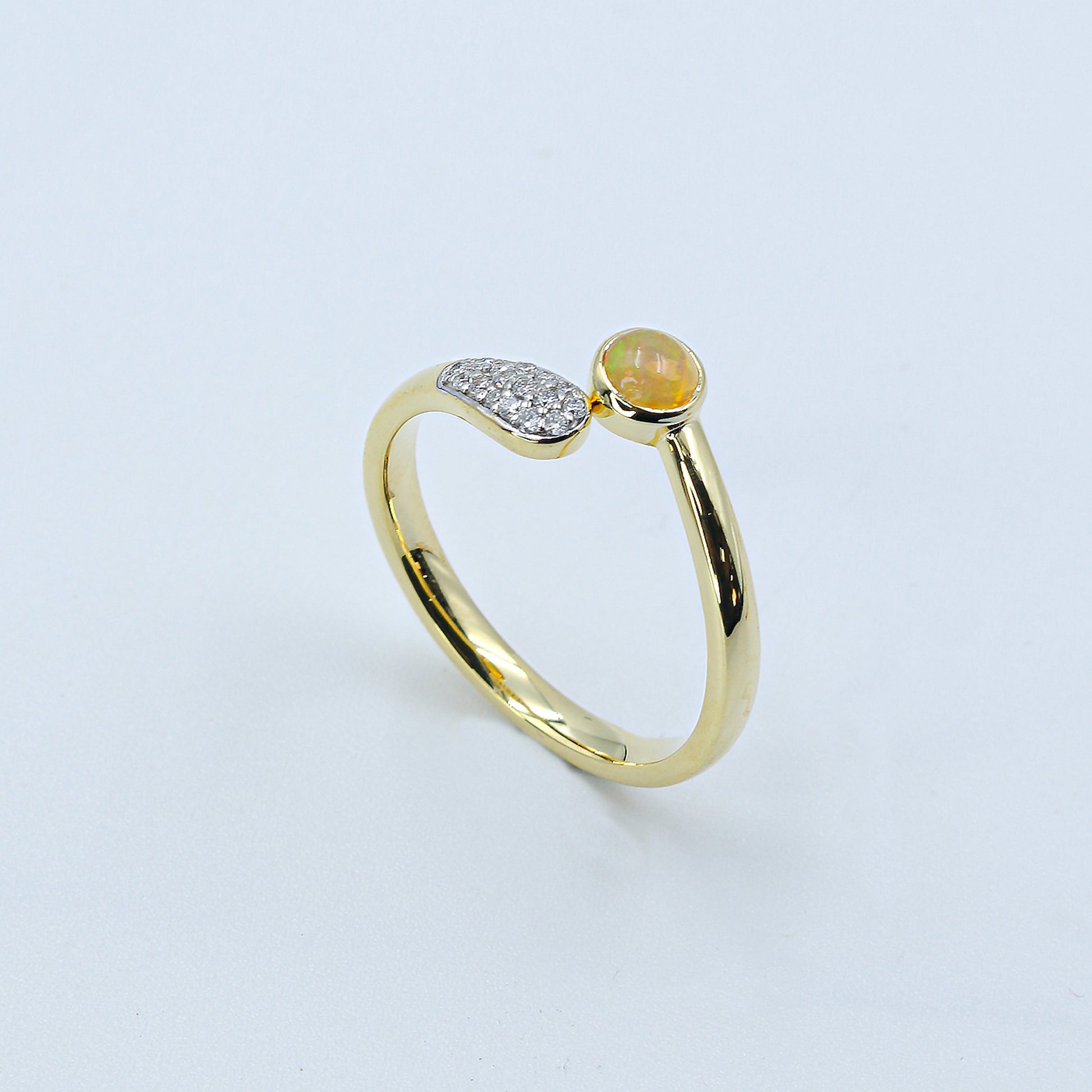 Gold ring with a green gemstone on a light gray background