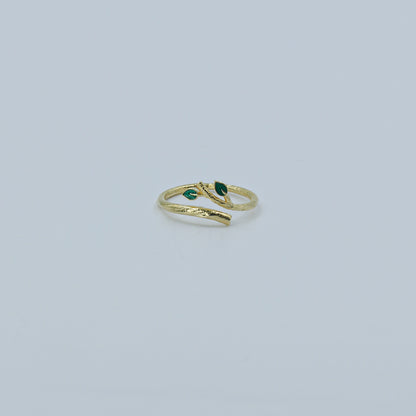 Gold ring with green gemstones on a light gray background