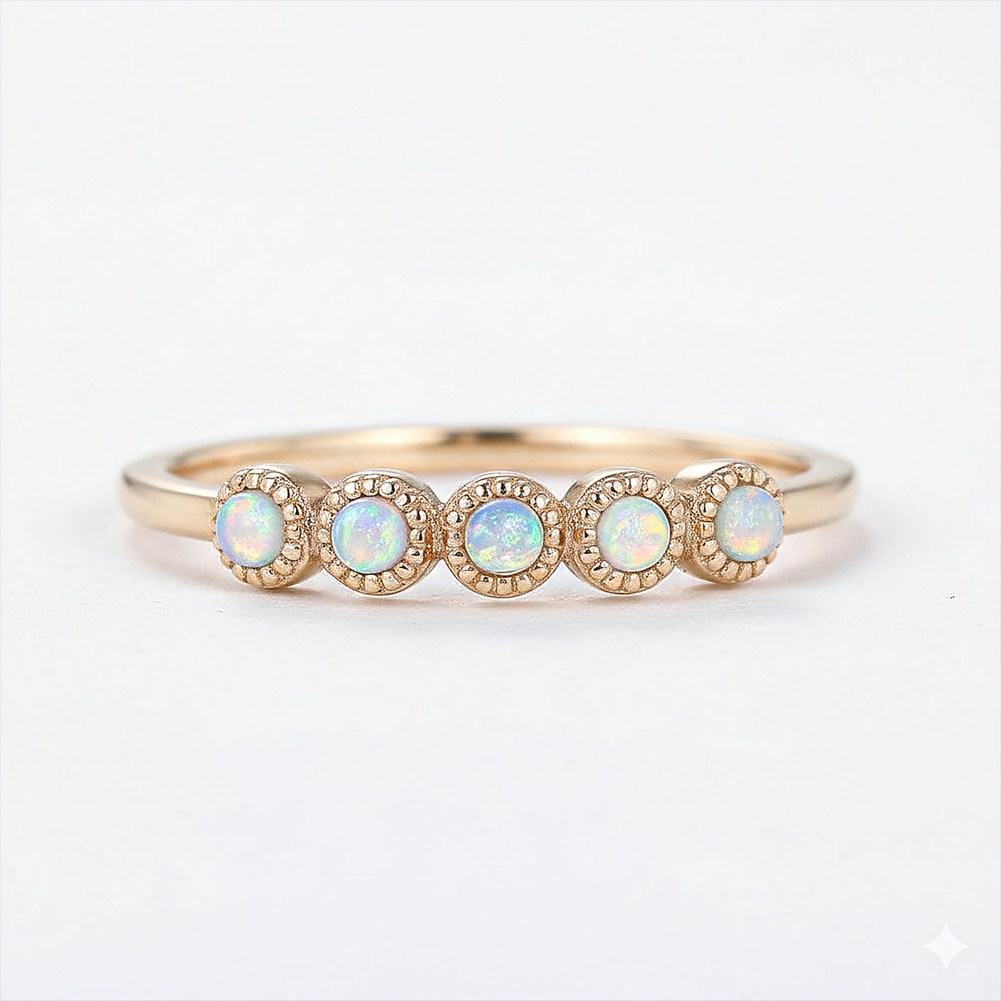 Gold ring with four opal stones on a white background