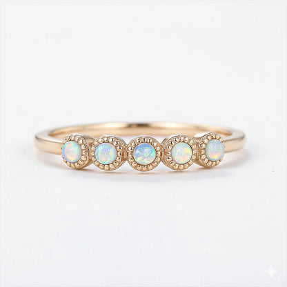 Gold ring with four opal stones on a white background