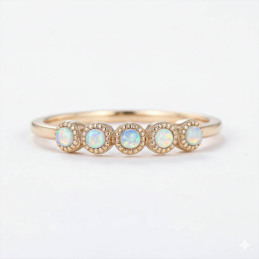 Gold ring with four opal stones on a white background