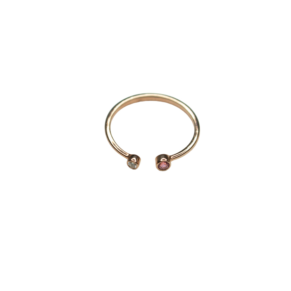Rose gold ring with embedded gemstones on a light gray background